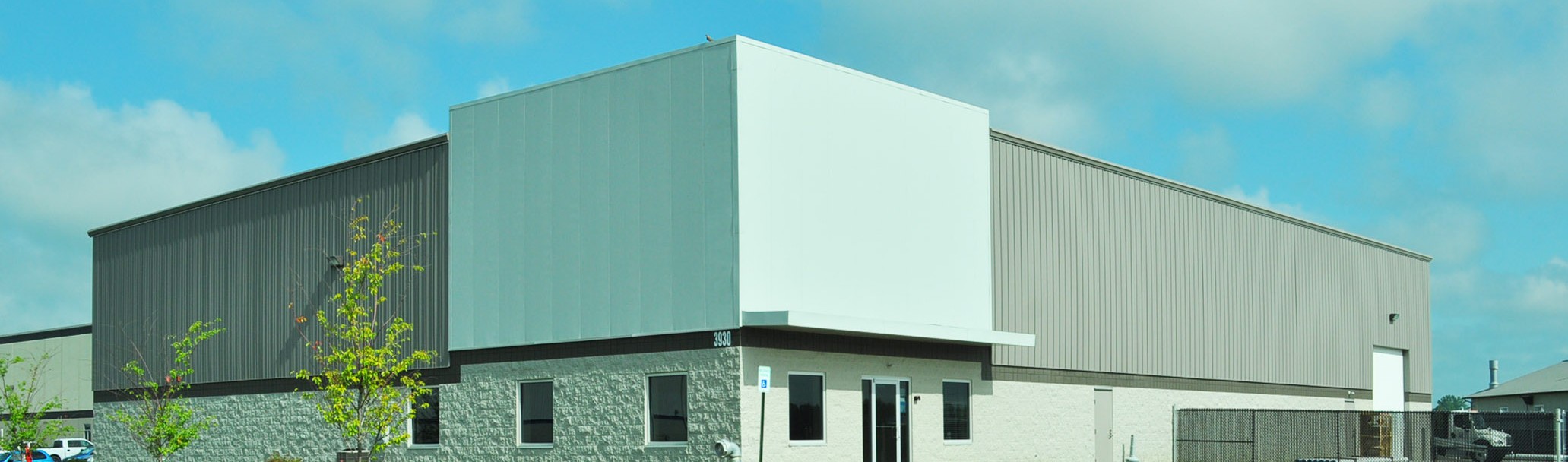 Two-tone gray pre-engineered metal building with stone wainscot, office entrance